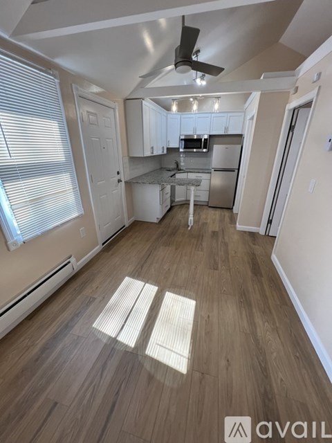 A spacious kitchen and living room with wood flooring and white walls.