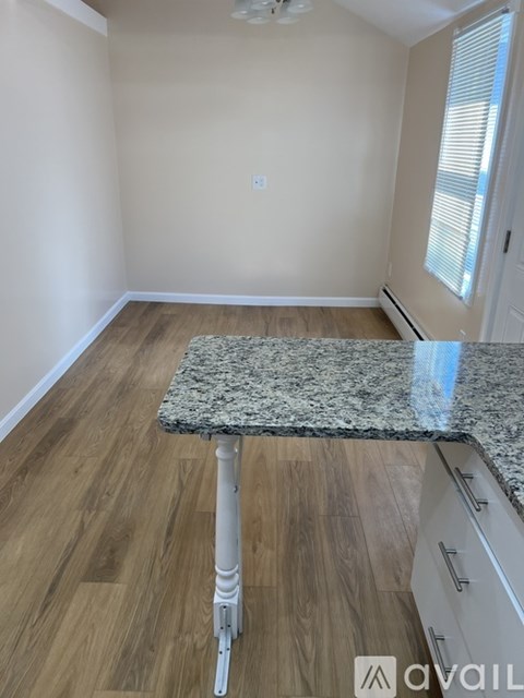 A room with a granite countertop and wooden flooring.