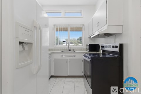 A kitchen with white cabinets and black countertops.