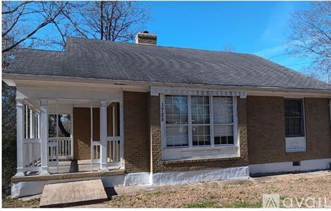 A small house with a porch and a brick exterior.