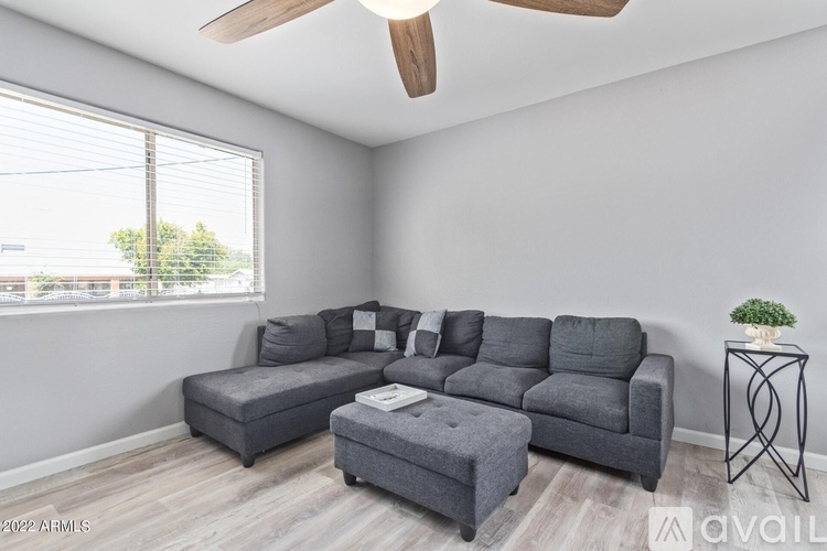 A living room with a grey sofa set and a small table with a plant on it.