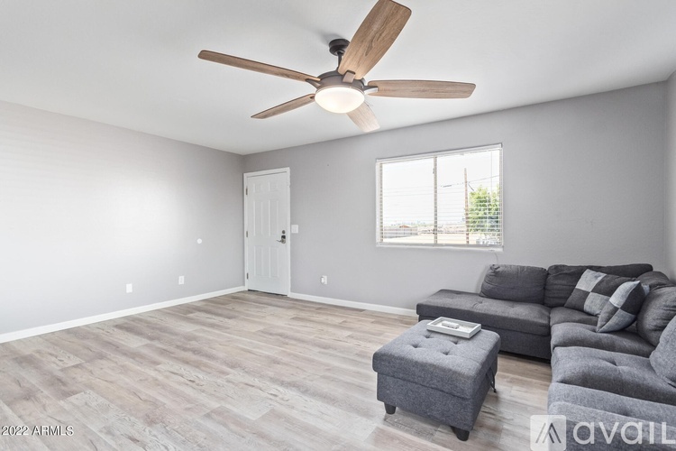 A living room with a grey couch and a ceiling fan.