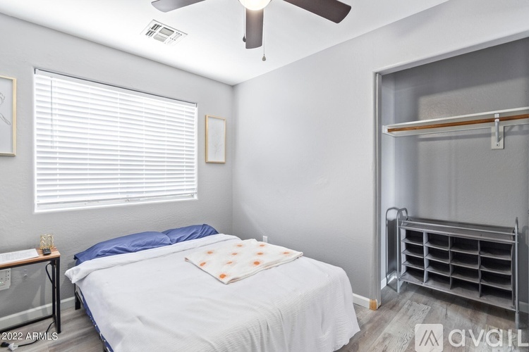 A bedroom with a bed, a ceiling fan, and a window with blinds.