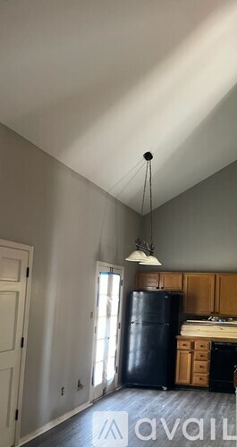 A kitchen with a black fridge and wooden cabinets.
