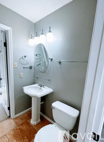 A bathroom with a toilet, sink, and mirror.