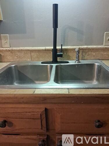 A double sink in a kitchen with a wooden drawer underneath.