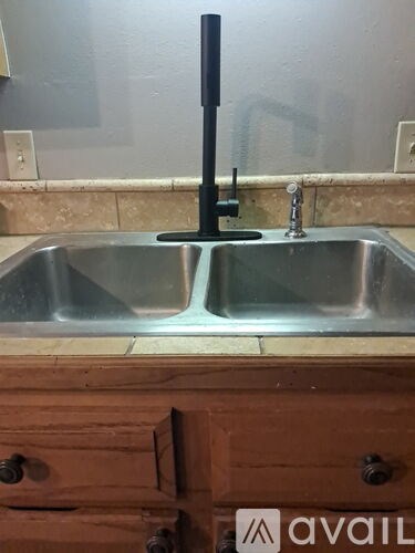 A double sink in a kitchen with a wooden drawer underneath.