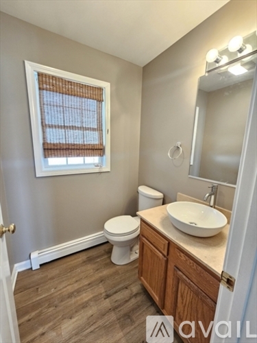 A bathroom with a toilet, sink, and window.