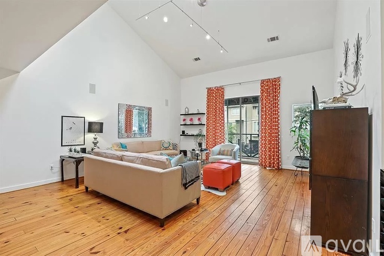 A living room with a beige couch and wooden floors.