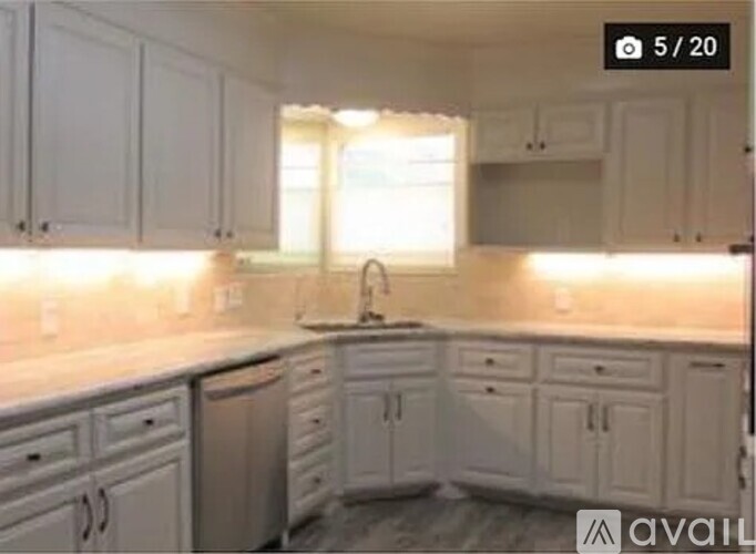 A kitchen with white cabinets and a sink under a window.