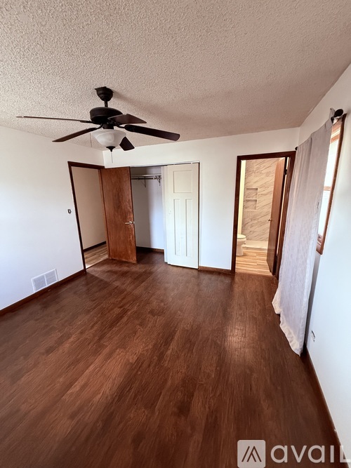 A room with a ceiling fan and wooden flooring.