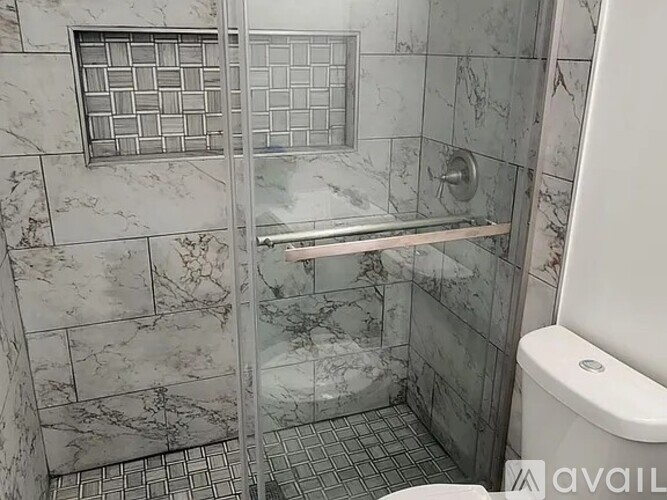 A bathroom with marble tiles and a walk-in shower.