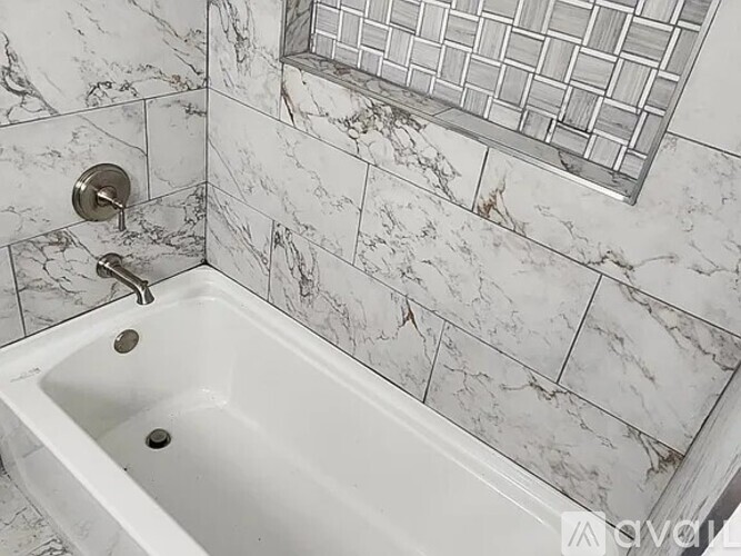 A white bathtub with a silver faucet and a silver shower head.