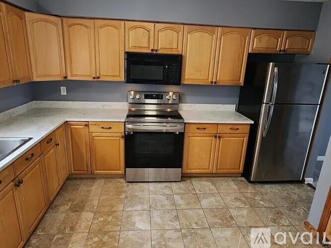 A kitchen with wooden cabinets and a stainless steel refrigerator.