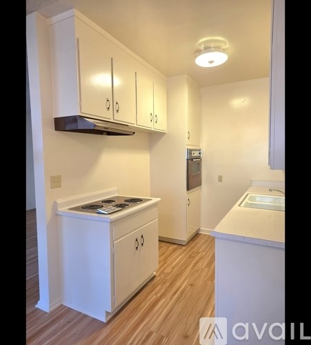 A kitchen with white cabinets and a stove top oven.