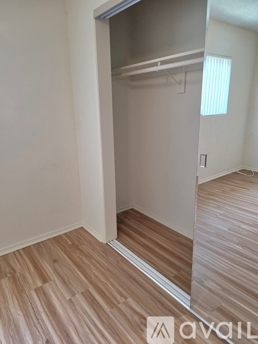 A room with a wooden floor and a white wall with a closet.