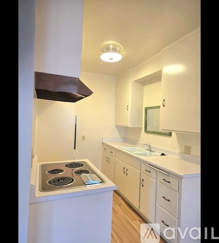 A kitchen with a stove top oven and white cabinets.