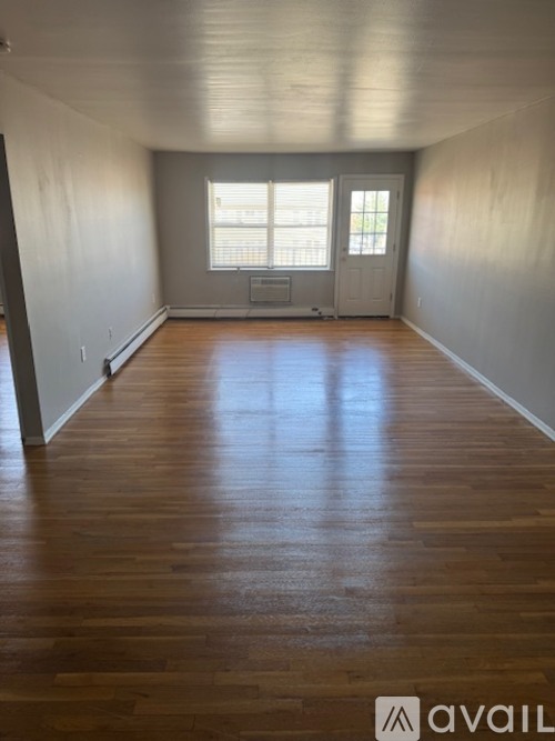 A room with wooden floors and a window with blinds.