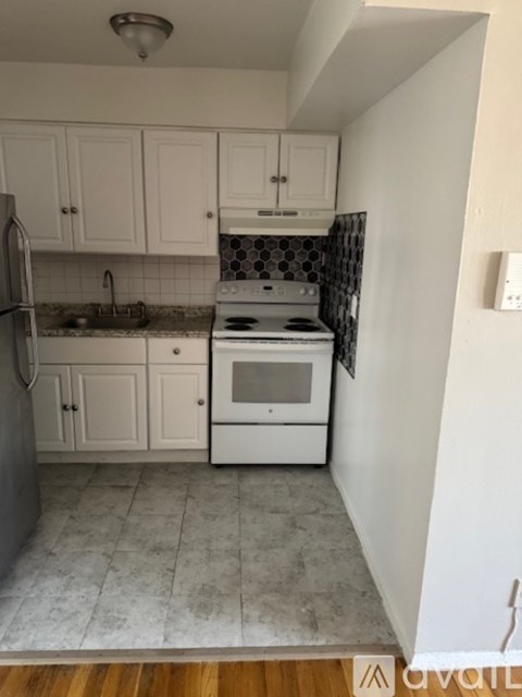 A kitchen with white cabinets and a black and white tiled backsplash.