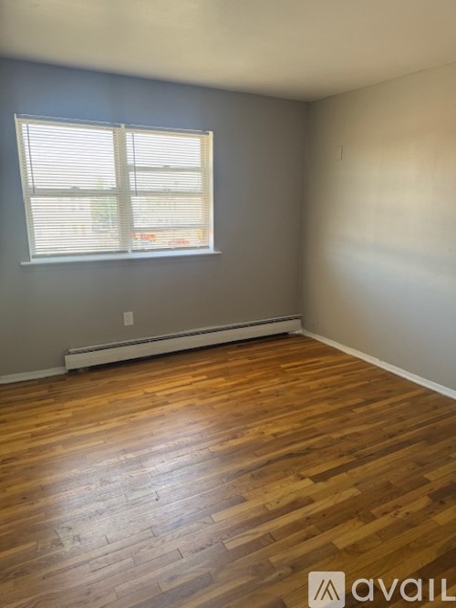 A room with wooden flooring and a window with blinds.