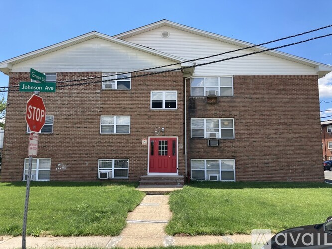 A brick building with a red door and a stop sign in front.
