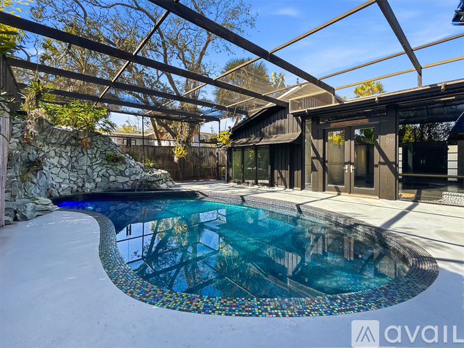 A pool with a glass wall and a stone wall with plants.