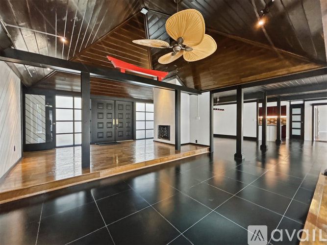 A spacious room with a ceiling fan and large windows.