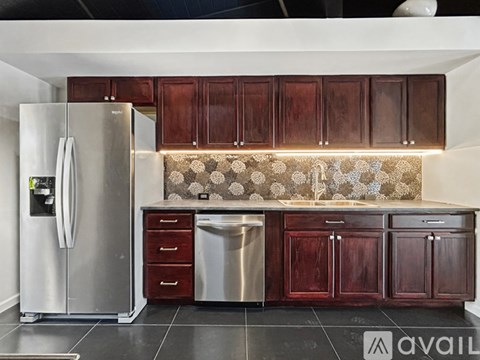 A kitchen with a stainless steel refrigerator and wooden cabinets.