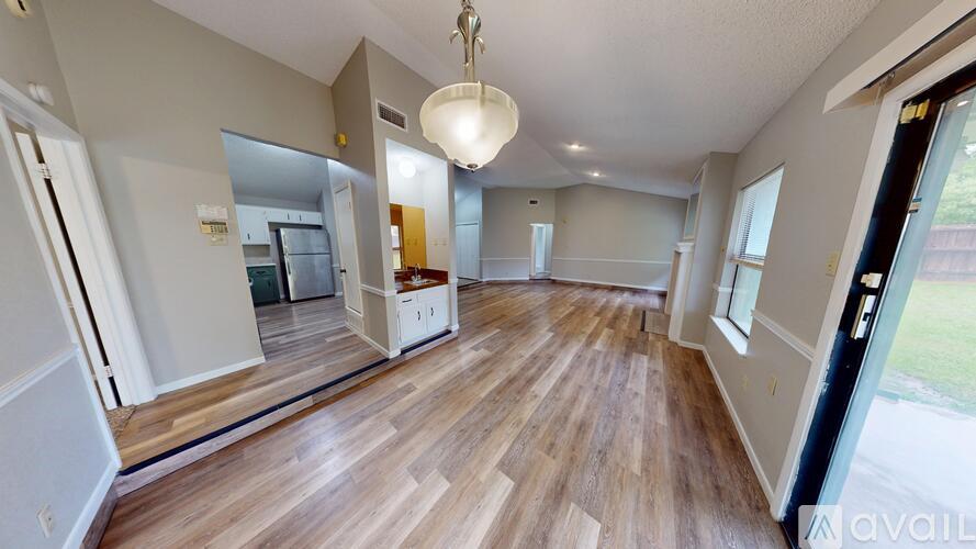 A spacious room with wooden flooring and a large mirror on the wall.