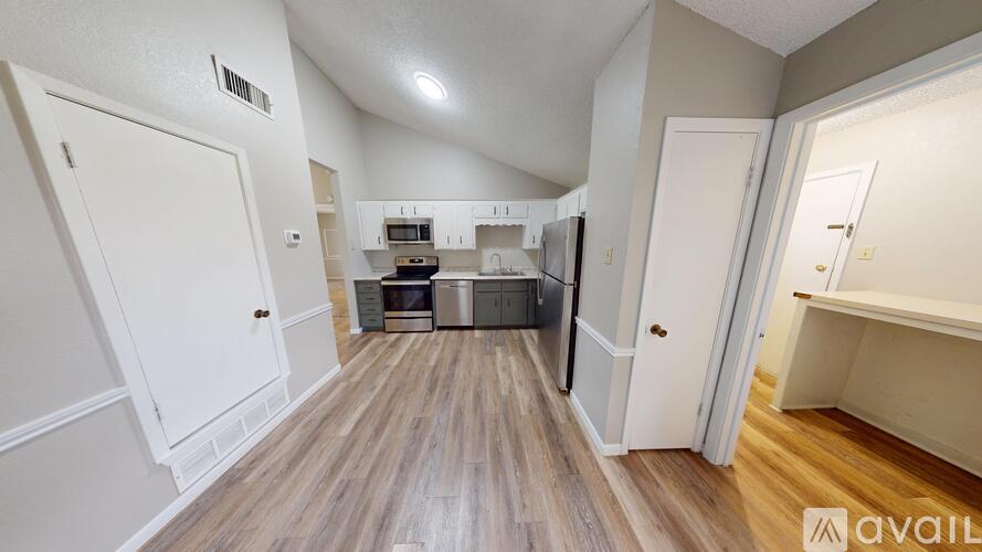 A kitchen with white cabinets and a wooden floor.