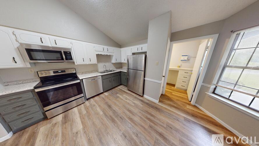 A kitchen with white cabinets and a wooden floor.