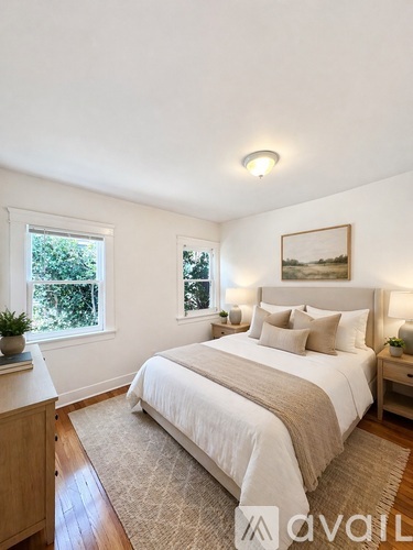 A bedroom with a large bed, a window with a view of trees, and a painting on the wall.