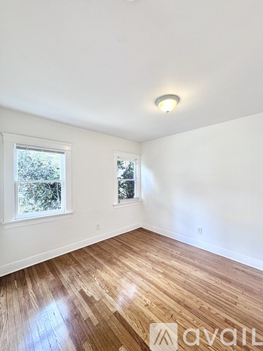 A room with wooden floors and two windows.