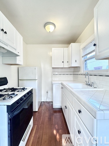 A kitchen with white cabinets and a black stove top.