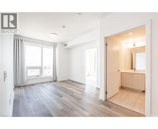 A spacious room with a wooden floor and a large mirror on the wall.