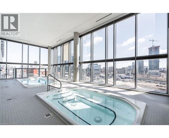 A large indoor swimming pool with a glass wall overlooking a cityscape.