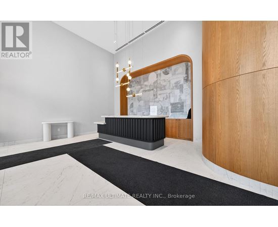 A modern office space with a wooden reception desk and a chandelier.