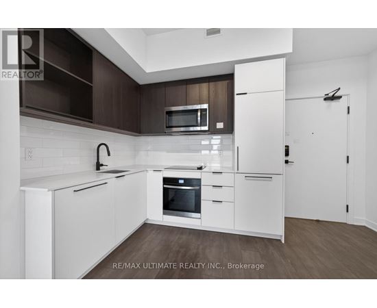 A modern kitchen with white cabinets and a wooden backsplash.