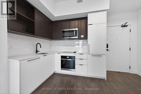 A modern kitchen with white cabinets and a wooden backsplash.