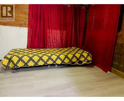 A black and yellow patterned mattress with a red curtain in the background.