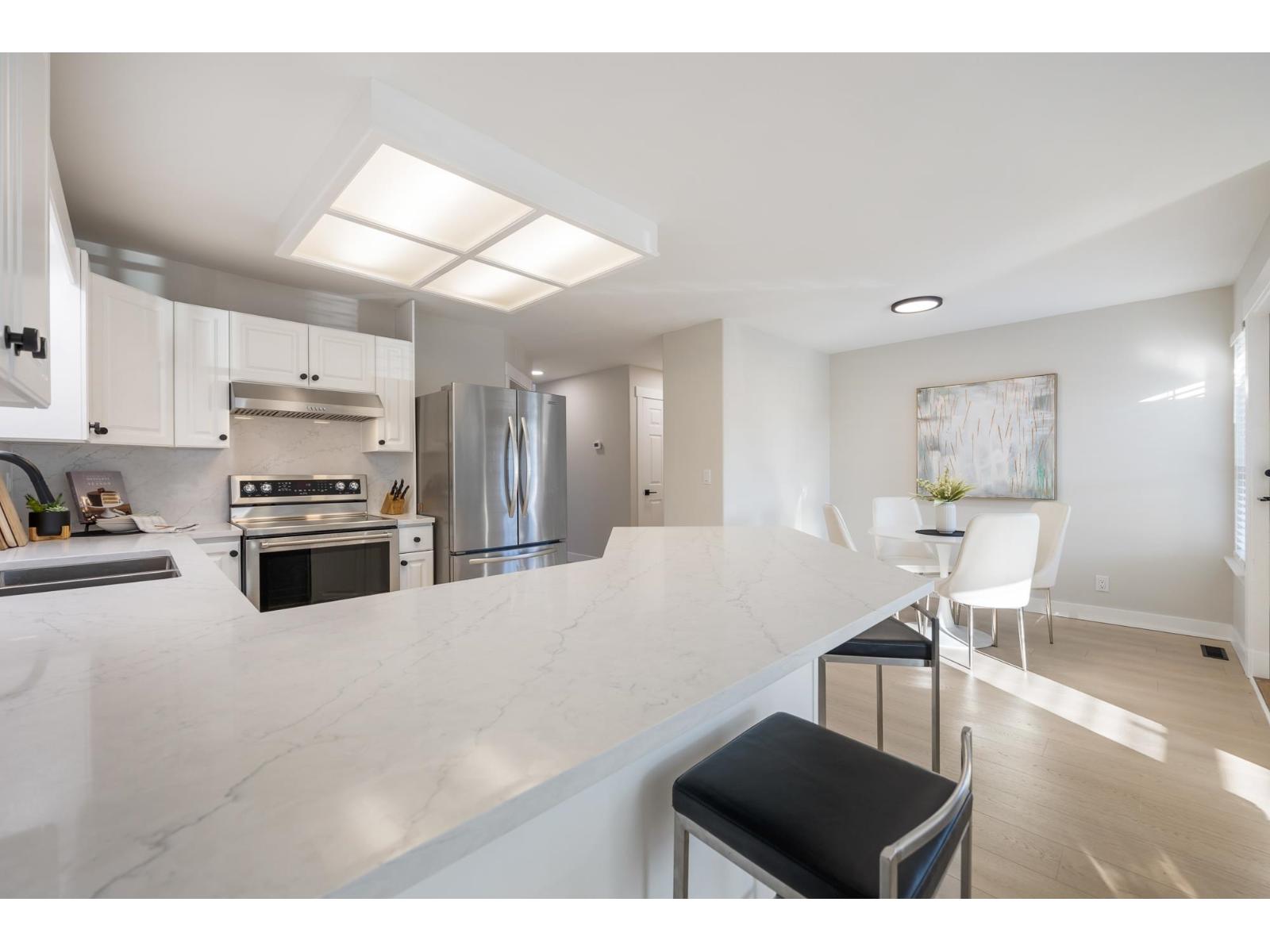 A modern kitchen with a marble countertop and stainless steel appliances.
