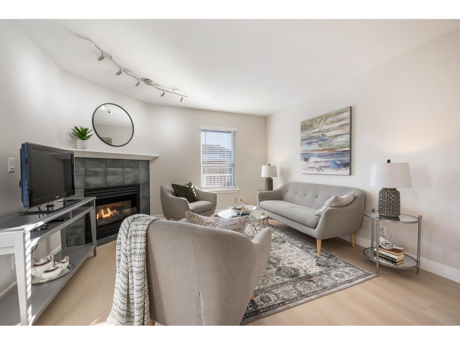 A living room with a grey couch, a fireplace, and a painting on the wall.