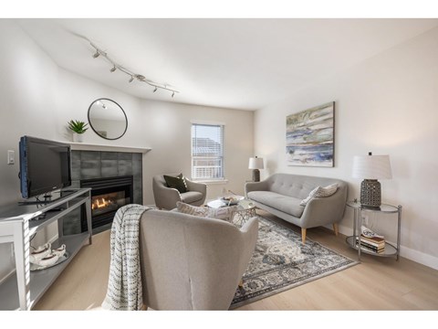 A living room with a grey couch, a fireplace, and a painting on the wall.