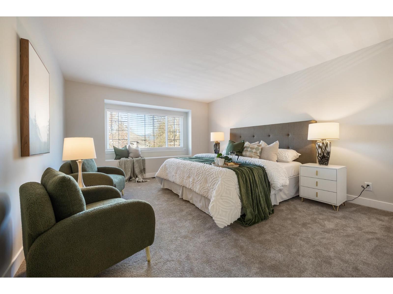 A bedroom with a large bed and a green chair.