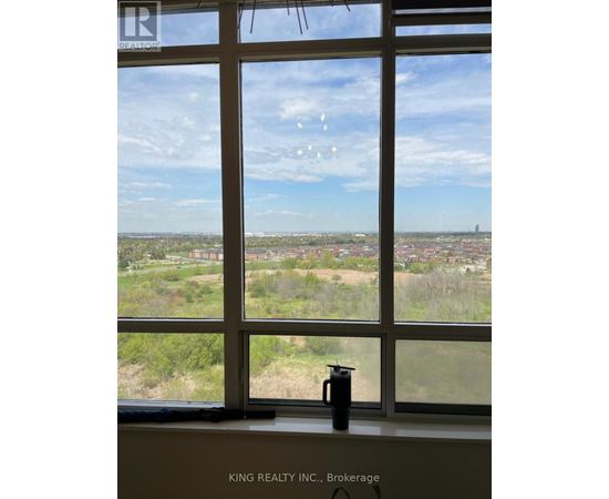 A window with a view of a cityscape and a kettle on the windowsill.