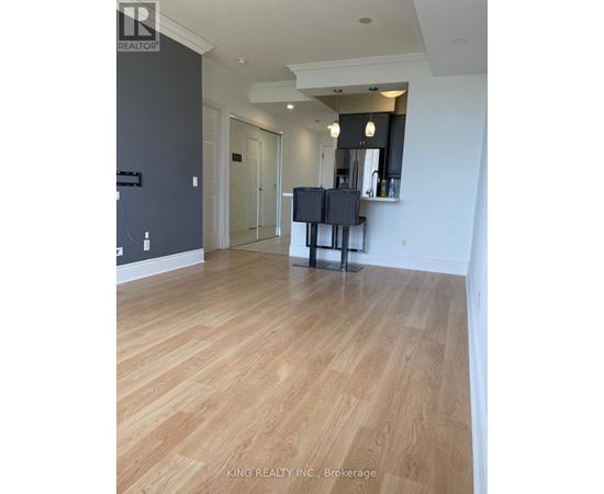 A spacious room with wooden flooring and a television on a stand.