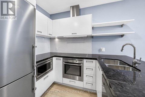 A modern kitchen with a stainless steel refrigerator and white cabinets.