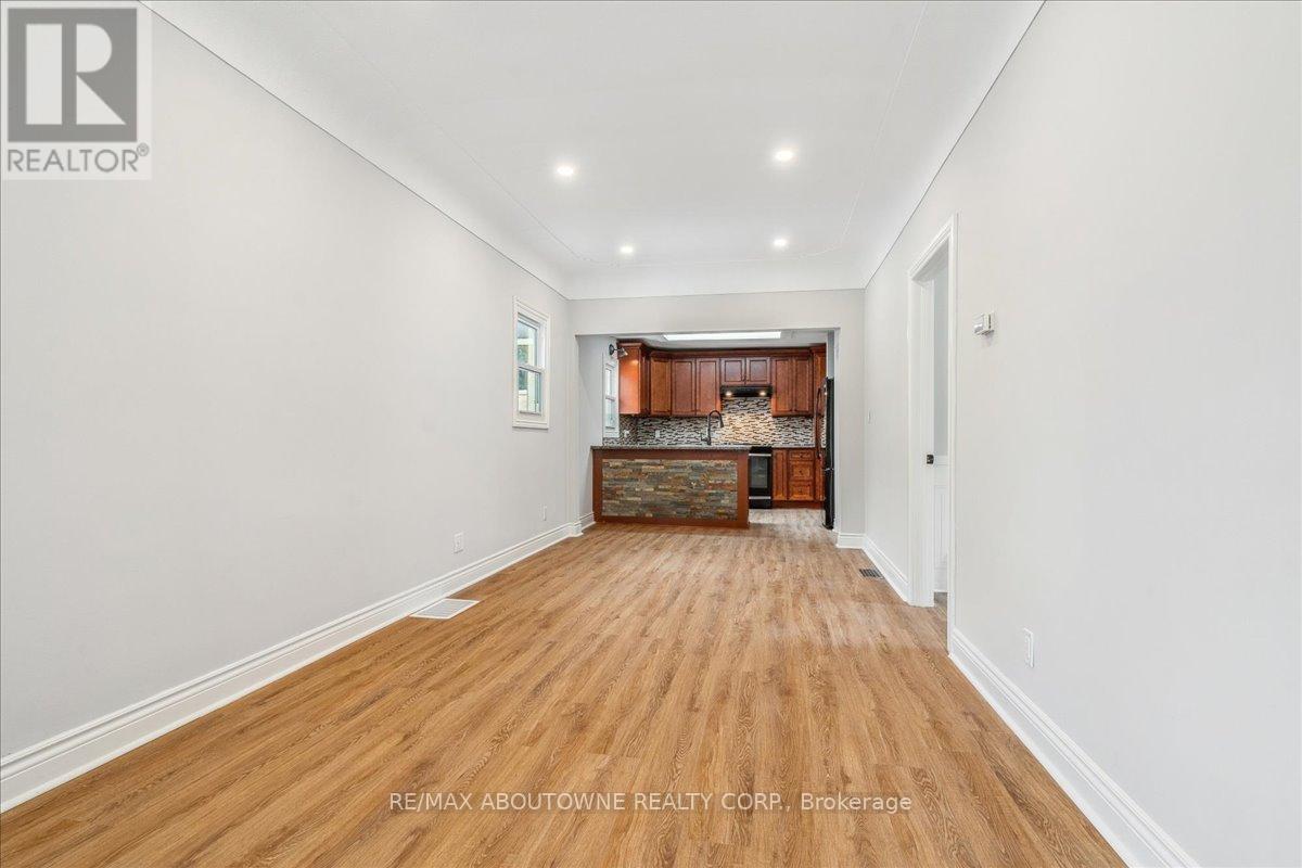 A spacious room with wooden flooring and a kitchen area in the background.