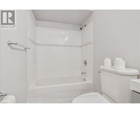 A white bathroom with a tub, toilet and sink.
