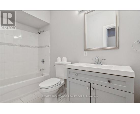 A white bathroom with a toilet, sink, and mirror.